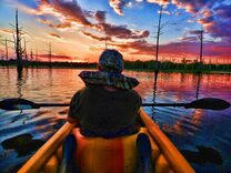 Kayaker enjoying vivid post-sunset clouds at Black Bayou Lake, Monroe, Louisiana..